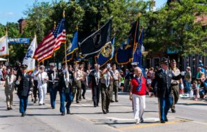 Veterans marching with flags during a patriotic parade.